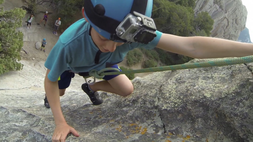 An individuals climbs up a rock.