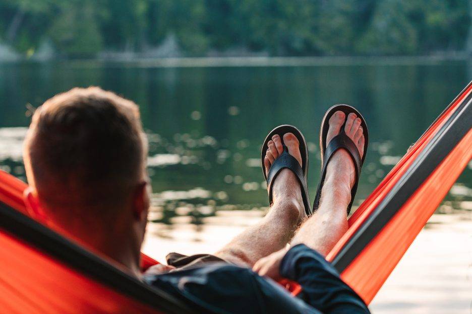 A man sits in a hammock while sporting Nuusol shoes.