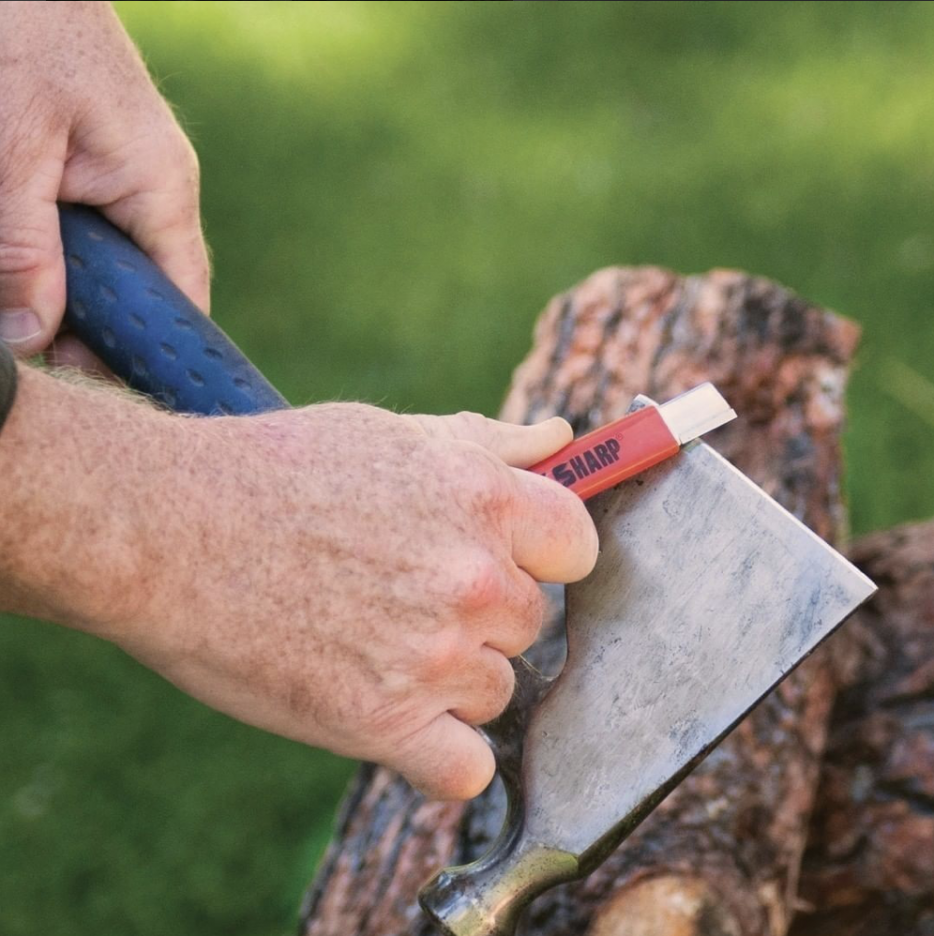 An individual uses a Speed Sharp tool to sharpen a dull axe.