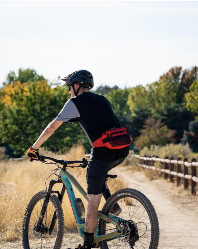 A cyclist wears a DMADA Trail Seeker Hip Pack.