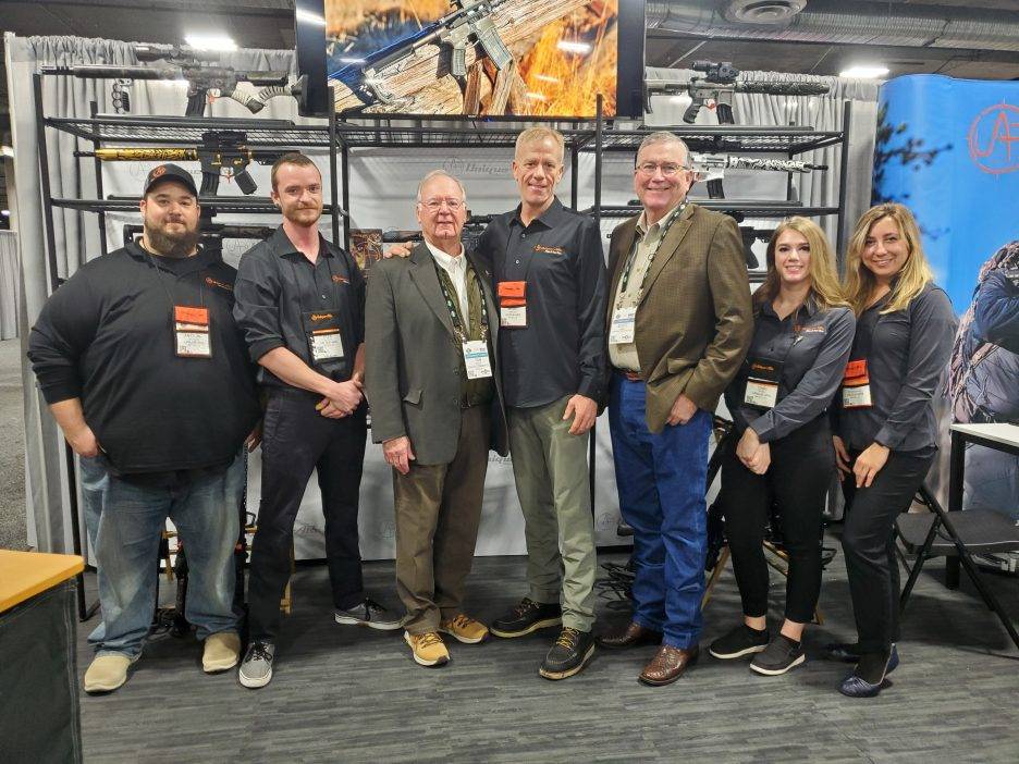A group attending SHOT Show poses for a group photo.