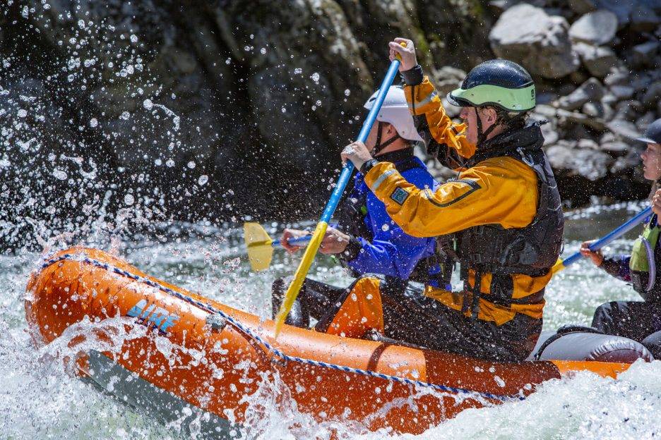 A group navigates whitewater rapids in an Aire raft.