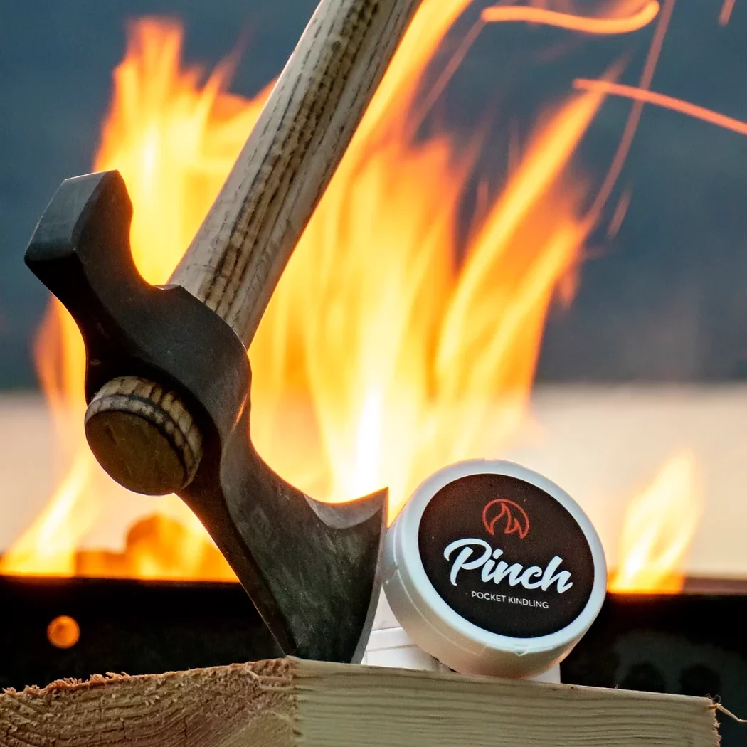 Pinch Pocket Kindling next to a hatchet with a fire int he background